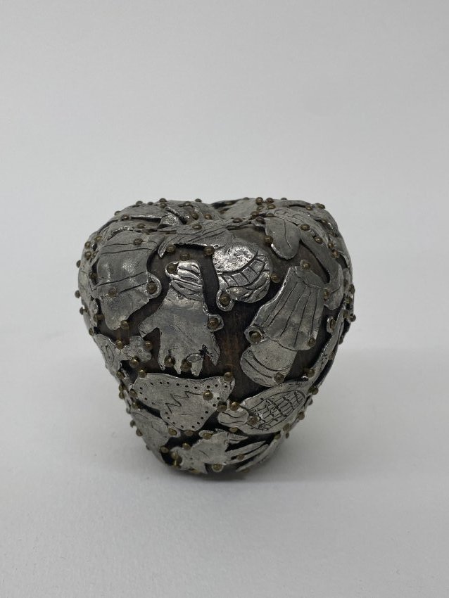 A apple with milagros from the Female Fetish series by Claudia DeMonte